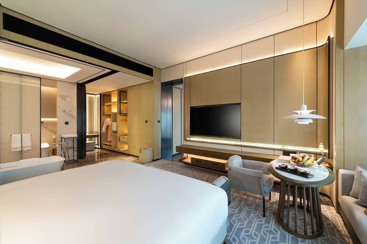 Une chambre d’hôtel moderne dotée d’un grand lit, d’une télévision, d’un coin salon et d’une salle de bain.