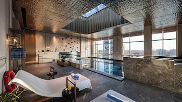 Un interior moderno con piscina, zona de estar y vistas a la ciudad.
