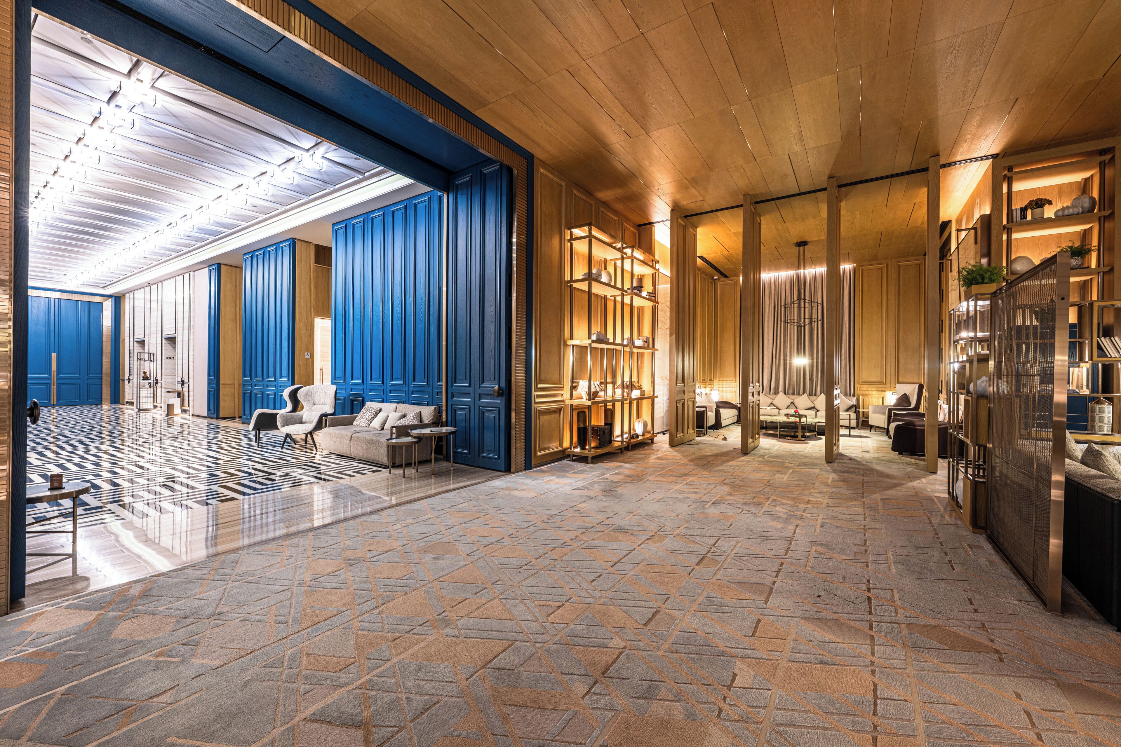 Un hall d’entrée spacieux, doté d’un sol à motifs, de portes bleues et d’un espace détente avec un canapé et des fauteuils.