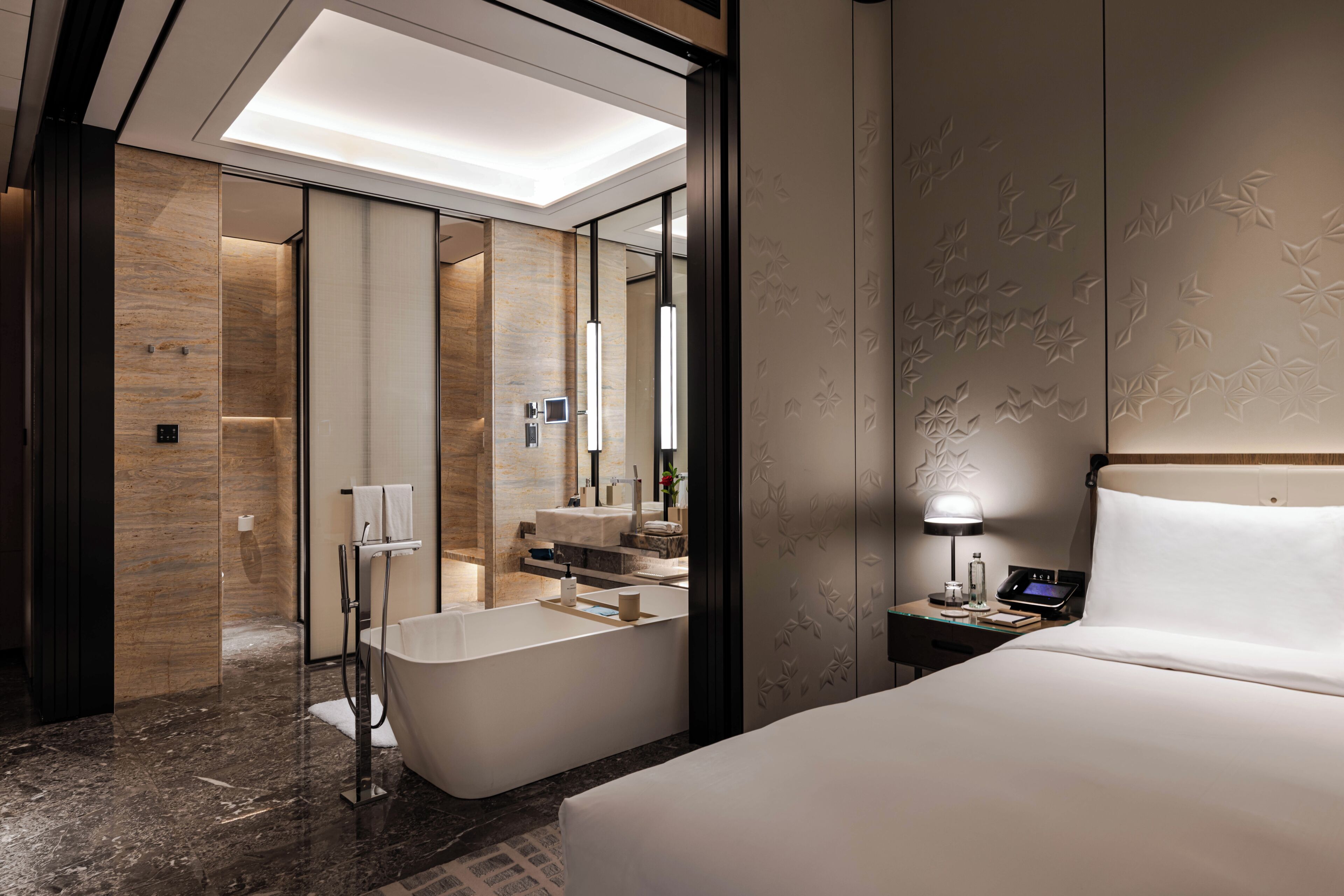 Une chambre d’hôtel moderne dotée d’un grand lit, d’une salle de bain séparée avec baignoire et d’un dressing.