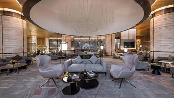 A spacious lobby with a central seating area, a high ceiling with a decorative light fixture, and a modern design.