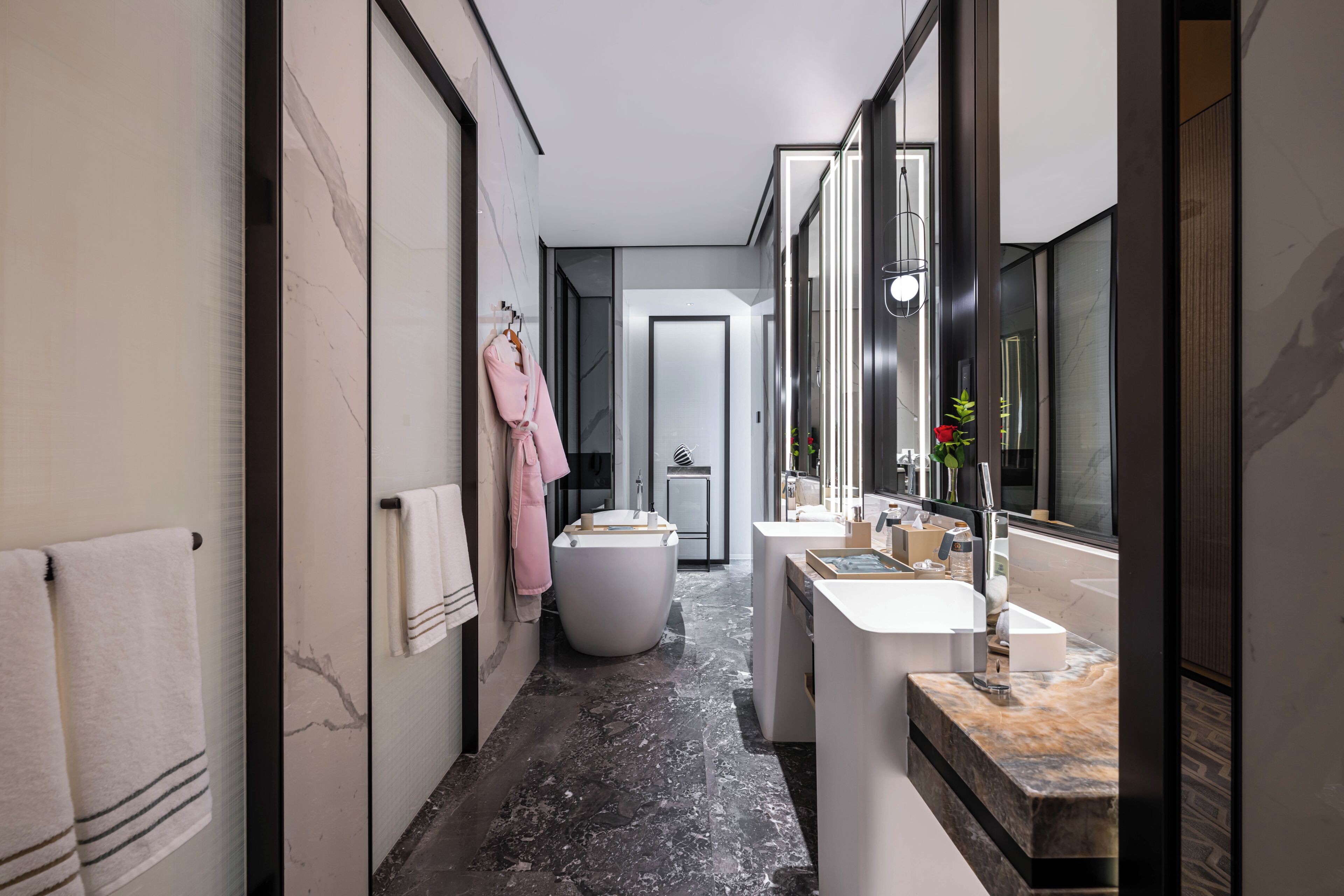 A modern bathroom with a marble floor, a large mirror, a bathtub, and a vanity with a sink.