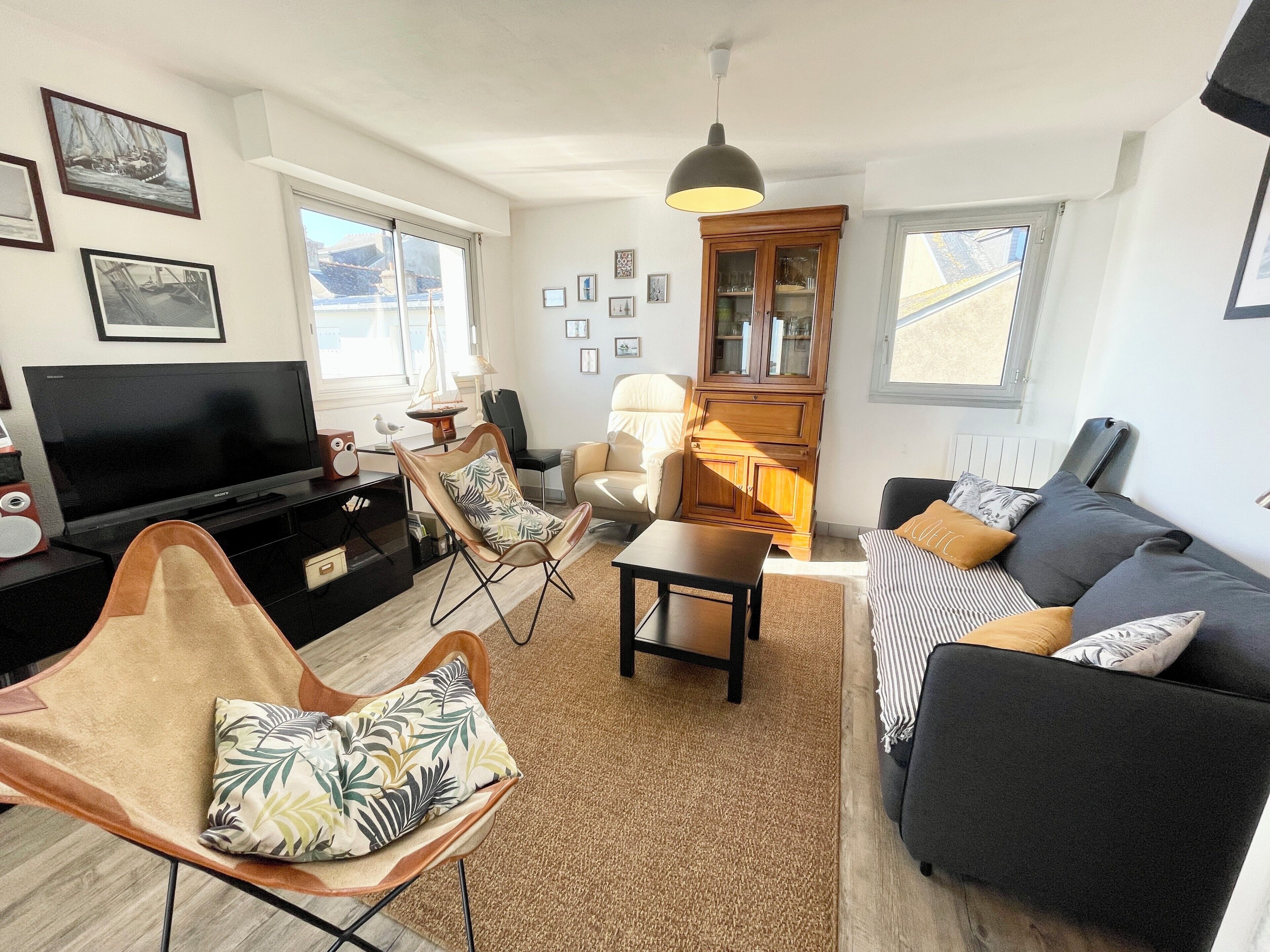 A living room with a sofa, armchair, TV, and a cabinet.