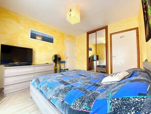 Ein Schlafzimmer mit einem Bett, einem Schminktisch, einem Fernseher und einem Spiegel.