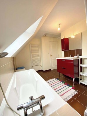Ein modernes Badezimmer mit einer freistehenden Badewanne, einem roten Waschtisch und einem großen Spiegel.