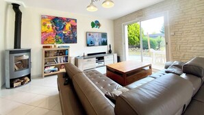 Un salon moderne avec une cheminée, un grand canapé, une table basse, un téléviseur et une bibliothèque.