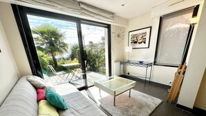 Un salon moderne avec un canapé, une table basse en verre et une vue sur l’extérieur.