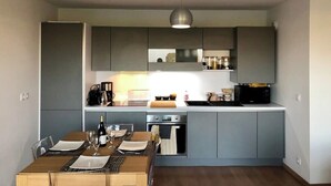 A modern kitchen with grey cabinets, a central island, and a dining area with a table set for two.