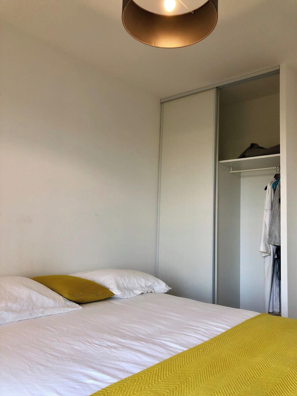A bedroom with a bed, a wardrobe, and a hanging coat rack.