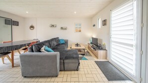 A modern living room with a sofa, a TV, and a dining area.
