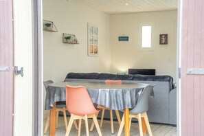 A dining area with a table, chairs, a sofa, and a television.