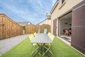 A patio with a table and chairs, a wooden fence, and a building with a garage door.
