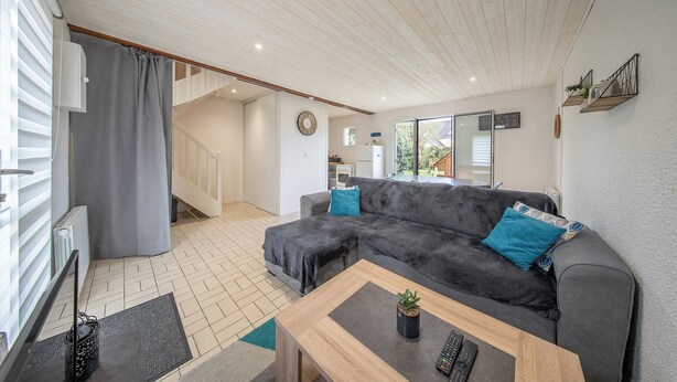 A living room with a grey sofa, a wooden coffee table, and a TV stand.