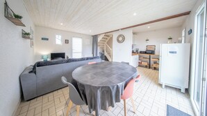 A modern interior with a grey sofa, round table, and chairs, a staircase, and a kitchen area.
