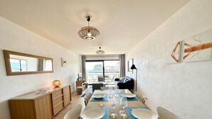 A dining area with a wooden table set for four, a large window, and a view of the city. - T3 Standing Vue Mer 180° Face Plage (Larmor-Plage)