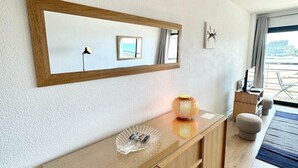 A modern living room with a wooden cabinet, a glass dish, a framed mirror, and a small framed picture on the wall. - T3 Standing Vue Mer 180° Face Plage (Larmor-Plage)