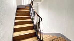 Eine Holztreppe mit schwarzer Metallgeländer, die zu einer Zwischenebene führt.