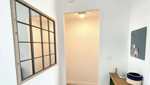 Ein Flur mit Holzboden, einer Tür mit Frostglas und einem kleinen Schreibtisch mit Korb, sowie einer Wandleuchte.