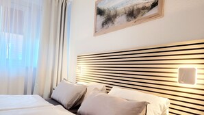A hotel room with a large bed, a headboard with horizontal slats, and a wall-mounted light fixture. - Vacation apartment Hovest - relaxation for up to 4 guests  (Ostbevern)