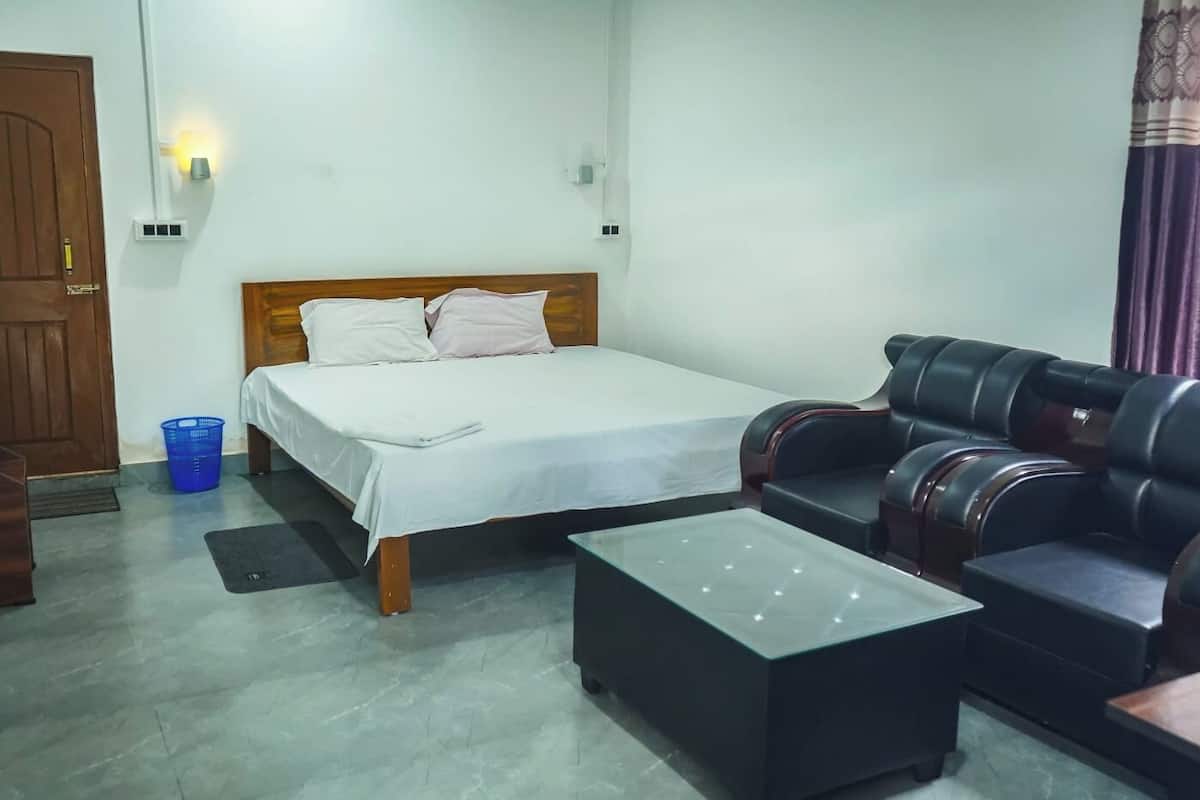 A bedroom with a bed, a sofa, and a small table.