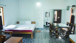 A room with a bed, wooden chairs, a small table, and a glass-top dining table. - Falcon Jungle Resort (Sarupeta)