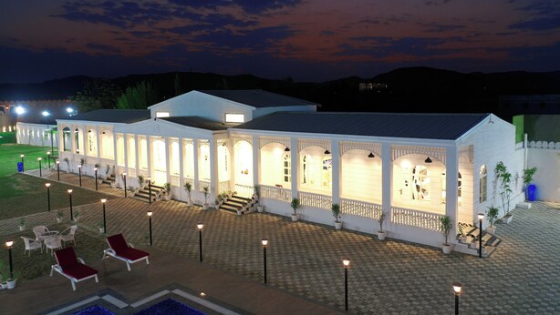 Un hotel con un área exterior techada, diversas opciones de asientos y una piscina.