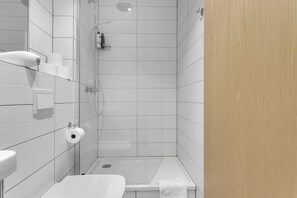 Une salle de bain moderne avec des carreaux blancs, une douche en verre et une porte en bois.