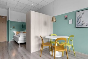 Una stanza moderna con un letto, un tavolino rotondo con sedie e una parete decorata con quadri.