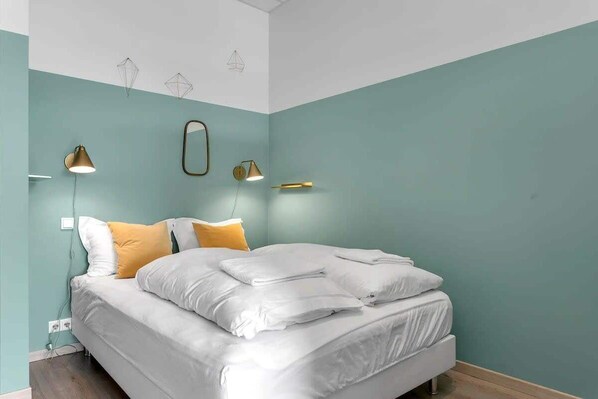 Una camera da letto con un letto, due lampade a parete e uno specchio.