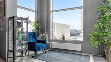 A modern room with large windows, a blue armchair, a glass cabinet, and a potted plant.