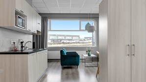 Une cuisine moderne avec une grande fenêtre, un canapé de couleur turquoise et une petite table sur laquelle est posé un vase.