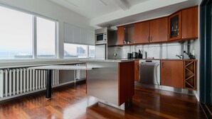 Cocina moderna con una isla grande, electrodomésticos de acero inoxidable, armarios de madera y vistas a la ciudad.