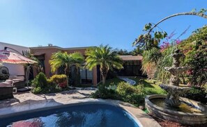 Relax by the serene pool surrounded by lush greenery and a variety of plants, complete with a soothing fountain.