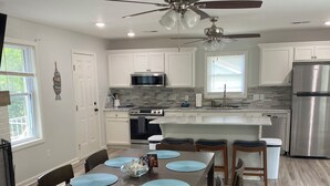 A modern kitchen with white cabinets, a stainless steel refrigerator, a microwave, and a stove. - Hot Tub / Top 1% /  Kayaks /  950 Mbp /  Pets /  PickleB (Hot Springs)
