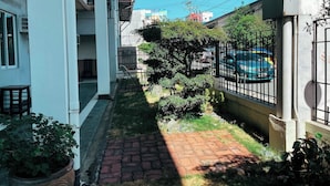 A narrow alleyway with a brick pathway, a metal fence, and a car parked on the right. - Siayan Travellers Inn Manila powered by Cocotel (Pasay)