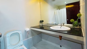 A modern bathroom with a toilet, sink, and mirror. - Siayan Travellers Inn Manila powered by Cocotel (Pasay)
