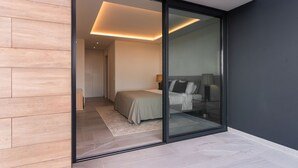 A modern bedroom with a glass door leading to a bathroom, featuring a bed, bedside table, and a lamp. - Buganvilia - Luxury villa - private pool by HD (Almancil)