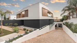 A modern two-story house with a flat roof, large windows, and a paved courtyard. - Buganvilia - Luxury villa - private pool by HD (Almancil)