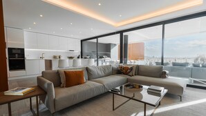 A modern living room with a sofa, coffee table, and a view of the city through large windows. - Buganvilia - Luxury villa - private pool by HD (Almancil)