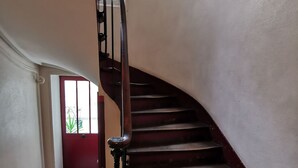 A wooden staircase with a handrail, leading to a landing with a red door and a window. - Bienvenue à Paris 19 :) (Paris)