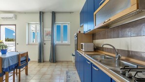 A modern kitchen with blue cabinets, a stainless steel sink, and a microwave. - 3866 Horizont - Bilo Standard by Barbarhouse (Margherita di Savoia)