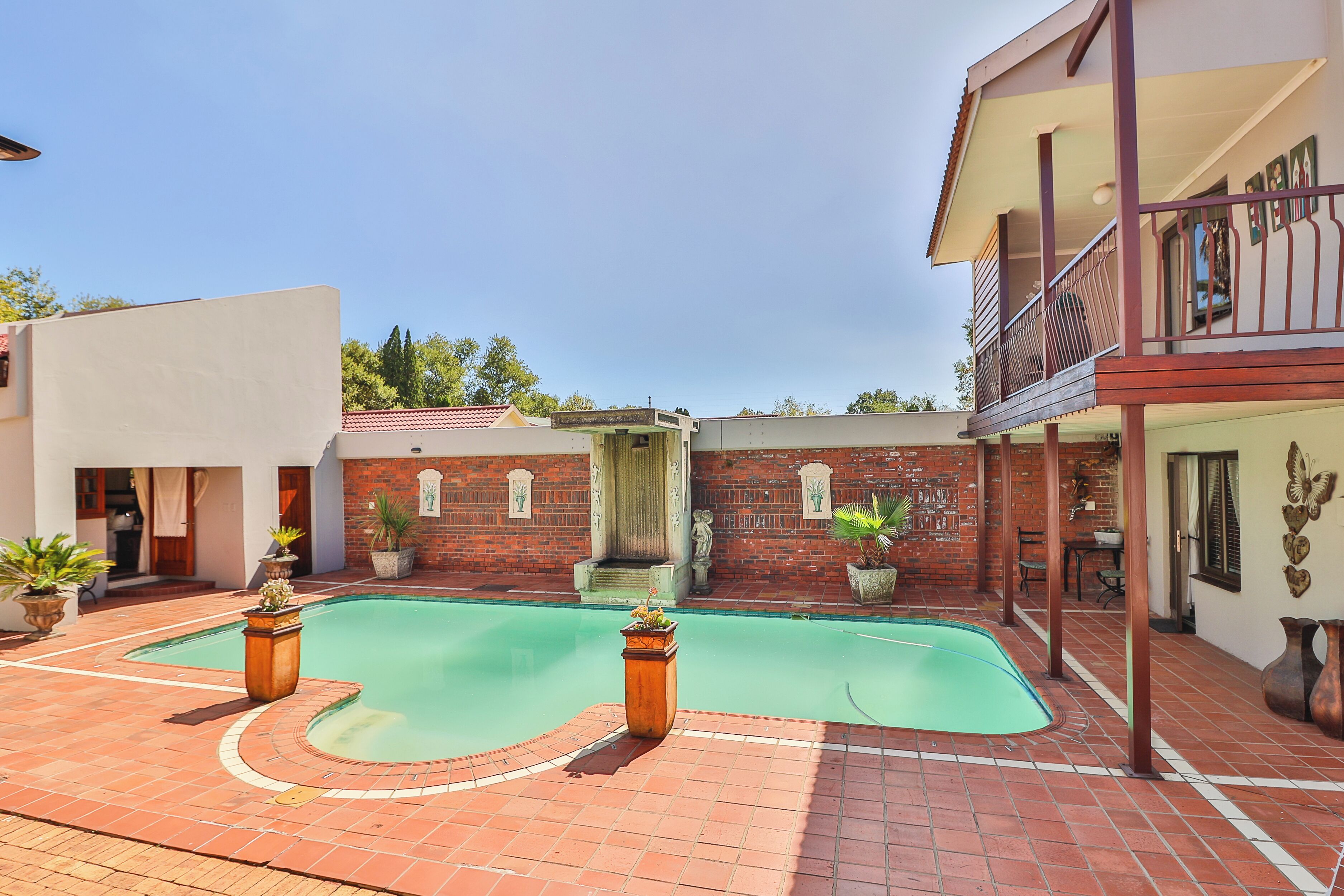 A swimming pool with a brick wall and a balcony.