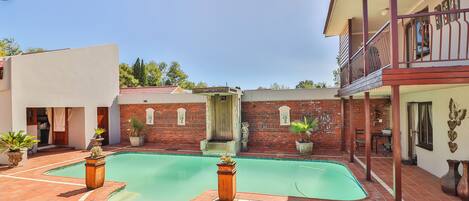 A swimming pool with a brick wall and a balcony.