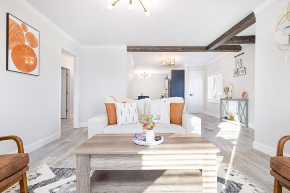 Un salon moderne avec un canapé blanc, une table basse en bois et un tapis.