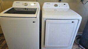 Deux lave-linge Samsung blancs, équipés de panneaux de commande, dont l’un a une porte en verre et l’autre une porte pleine.