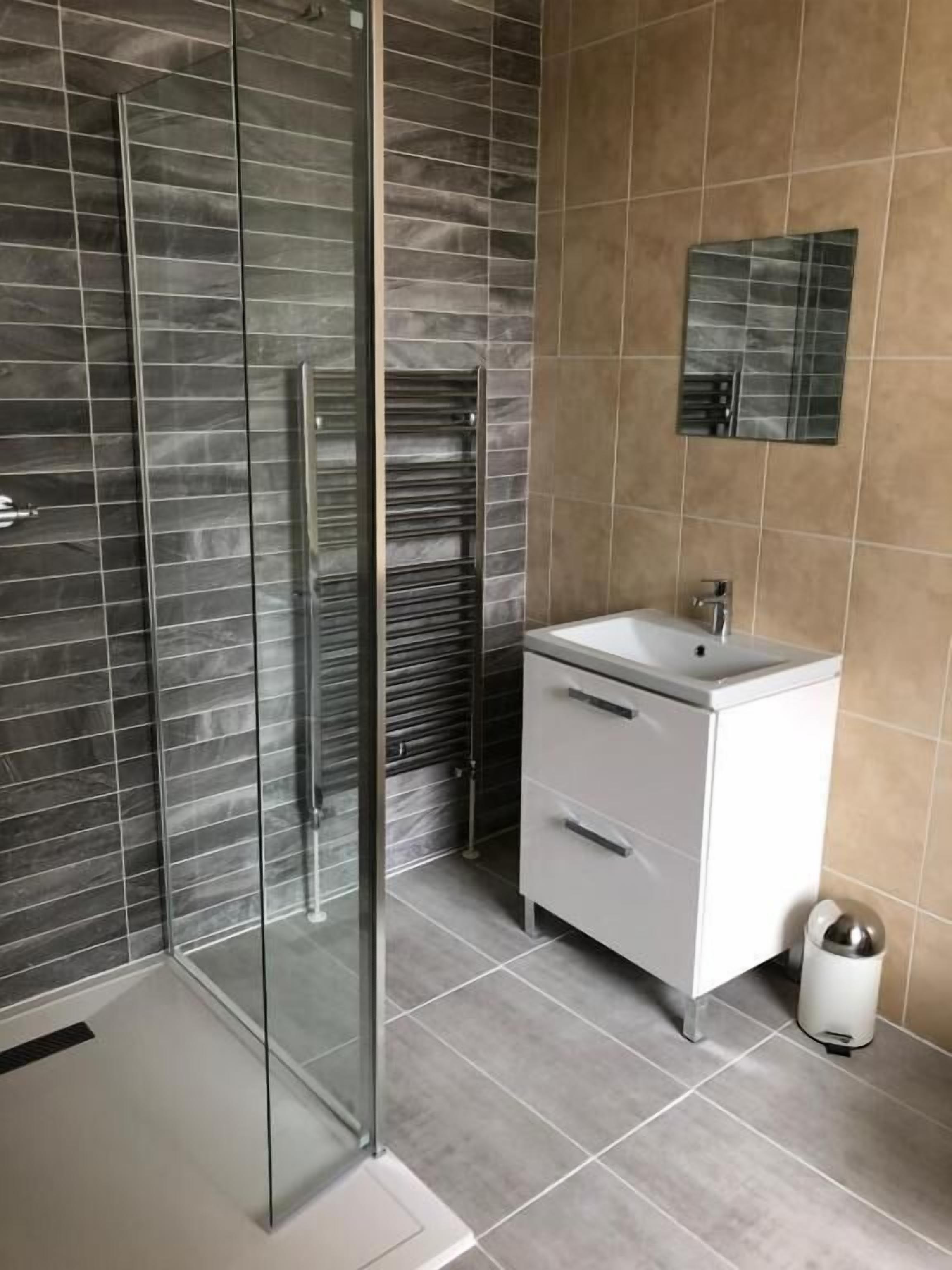 Un bagno moderno con box doccia in vetro, lavandino bianco e specchio a parete.
