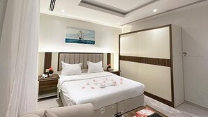 A modern hotel room with a large bed, a bedside table with a lamp, a wardrobe, and a painting on the wall. - Tamaya Alkhobar (Al Khobar)