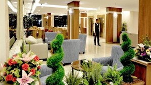 A hotel lobby with seating areas, a reception desk, and a person standing in the background. - Tamaya Alkhobar (Al Khobar)