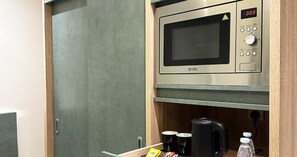 A compact kitchenette with a microwave, a coffee maker, and a small cabinet. - Tamaya Alkhobar (Al Khobar)