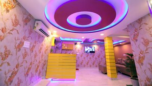 A room with floral wallpaper, a circular ceiling design, a TV, and a yellow partition. - Jupiter Plaza (New Delhi)